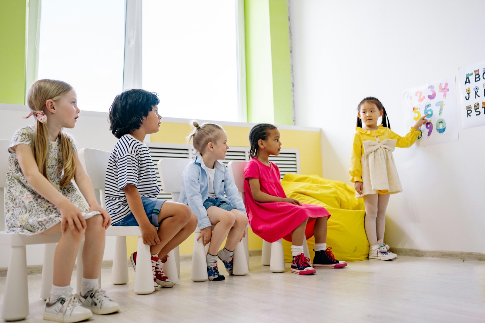 Children participating in a colorful classroom lesson with numbers on the wall.